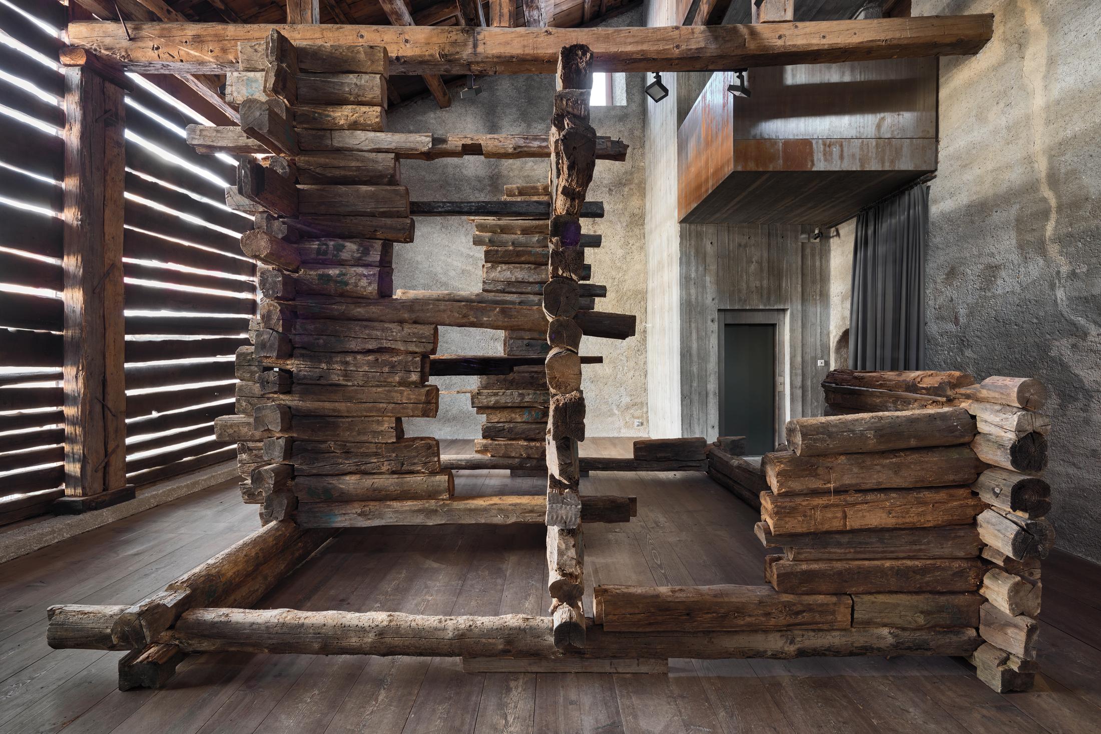Exhibition View Augustas Serapinas Solo Show «Wood and Snow; view on Augustas Serapinas, Remains of the House from Skirgiškės, 2022, Reclaimed Wood, 370 x 480 x 500 cm» at Galerie Tschudi, Zuoz, 2022-2023 / Photo: Raphael Feiner / Courtesy: the artist and Galerie Tschudi