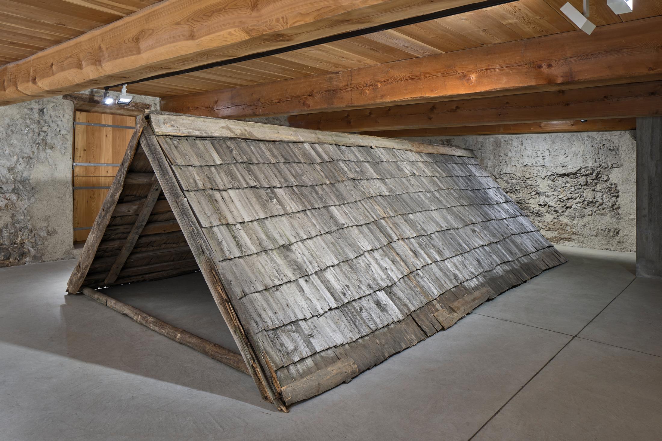 Exhibition View Augustas Serapinas Solo Show «Wood and Snow; view on Augustas Serapinas, Remains of the House from Skirgiškės, 2022, Reclaimed Wood, 370 x 480 x 500 cm» at Galerie Tschudi, Zuoz, 2022-2023 / Photo: Raphael Feiner / Courtesy: the artist and Galerie Tschudi