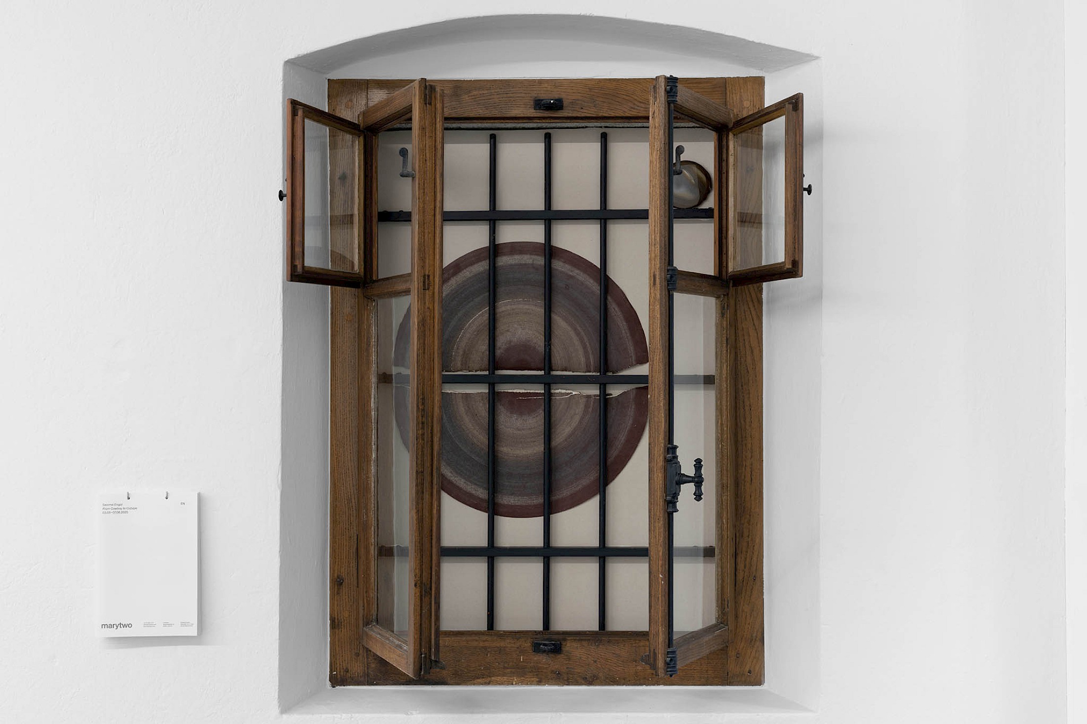 Exhibition View Salomé Engel Solo Show «From Cowboy to Cobaye; view on Salomé Engel, Substantive Revolutions, 2025, Sand paper, quartz stone disk, window, 137 × 99 × 53cm» at marytwo, Lucerne, Switzerland, 2025 / Photo: marytwo / Courtesy: the artist and marytwo