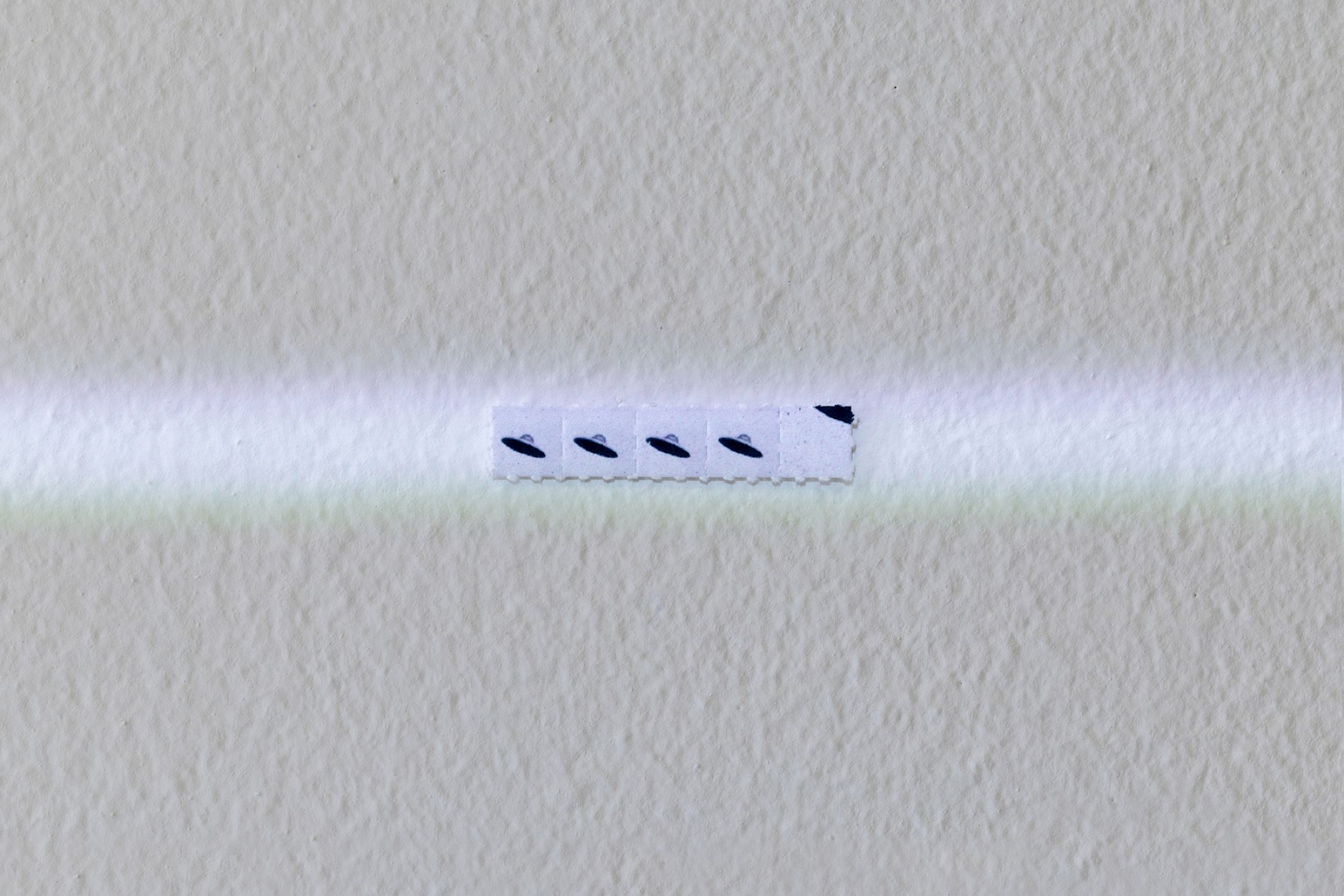 Exhibition View Solo Show Hunter Longe «Entgleitungen ; view on the past inserts a finger into a slit on the skin of the present and pulls 4, 2025, meteorite fragment (~5000 years old, Argentina), LSD blotter tabs, projector, video loop, Dimensions variable» at City SALTS, Baselland, 2025-2026 / Photo: Nicolas Gysin / Courtesy: the artist and City SALTS