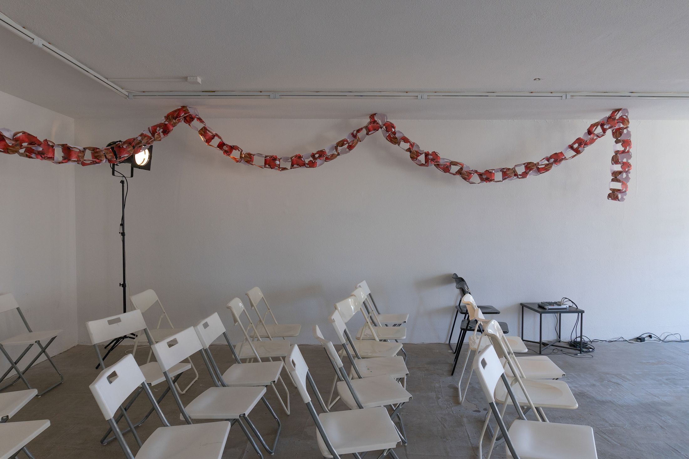 Exhibition View Solo Show Sven Gex «celebratory ; view on Sven Gex, garland for ‚celebratory‘ (maid-of-all-work character), 2025, hand cut printed pictures, staples and Sophie Becker, Setup of “Ronnie’s World”, Performance during the opening night» at Halmet, Zurich-Oerlikon, 2025 / Photo: Tereza Glazova / Courtesy: the artist and Halmet