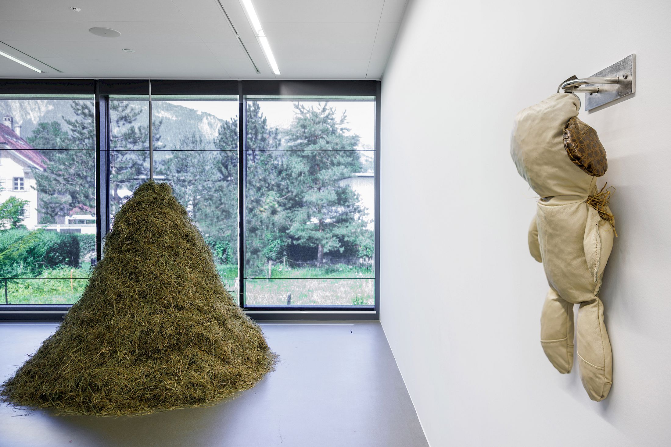 Exhibition View Dorota Gawęda & Eglė Kulbokaitė Solo Show «Death by Landscape; view on Dorota Gawęda & Eglė Kulbokaitė, Hexanol (IV), 2020, polished steel, meadow hay, 230 x 100 x 96 cm and Kratt, 2021, recycled leather, hay, chromed steel fixtures, dimensions variable» at Haus für Kunst Uri, Altdorf, 2025 / Photo: Franz-Xaver Brun / Courtesy: the artists and Haus für Kunst Uri