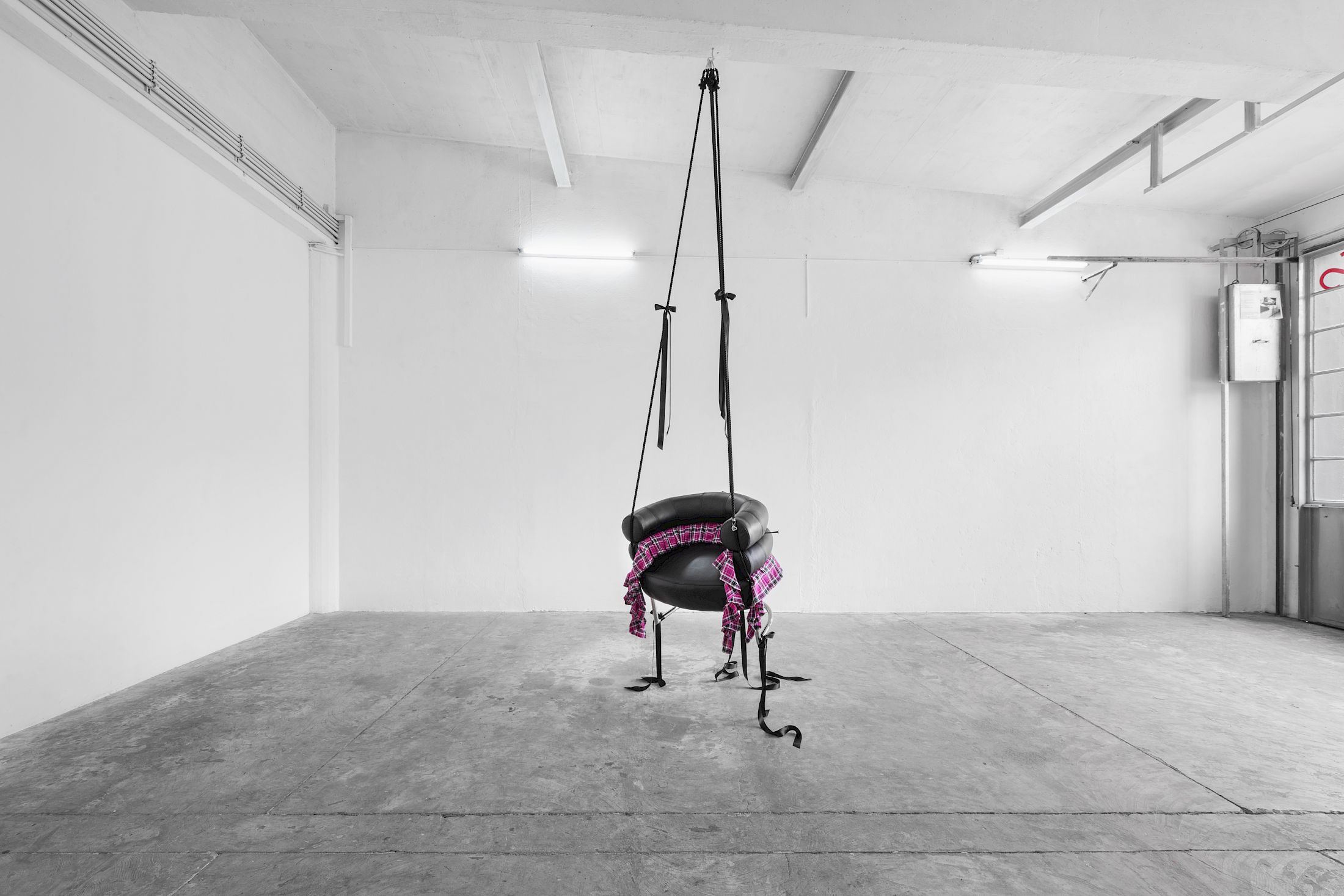 Exhibition View Solo Show Lauryn Youden «I wanna hold the hand inside you ; view on Would you die tonight for love?, 2025, Bibendum Chair (1926), pink plaid skirt, black ribbons, black mooring line, heart locket necklace with red hair, 3x handforged nails, 370 × 93 × 77 cm (suspended)» at CIRCUIT, Lausanne, 2025 / Photo: Aude Mayer / Courtesy: the artist and CIRCUIT
