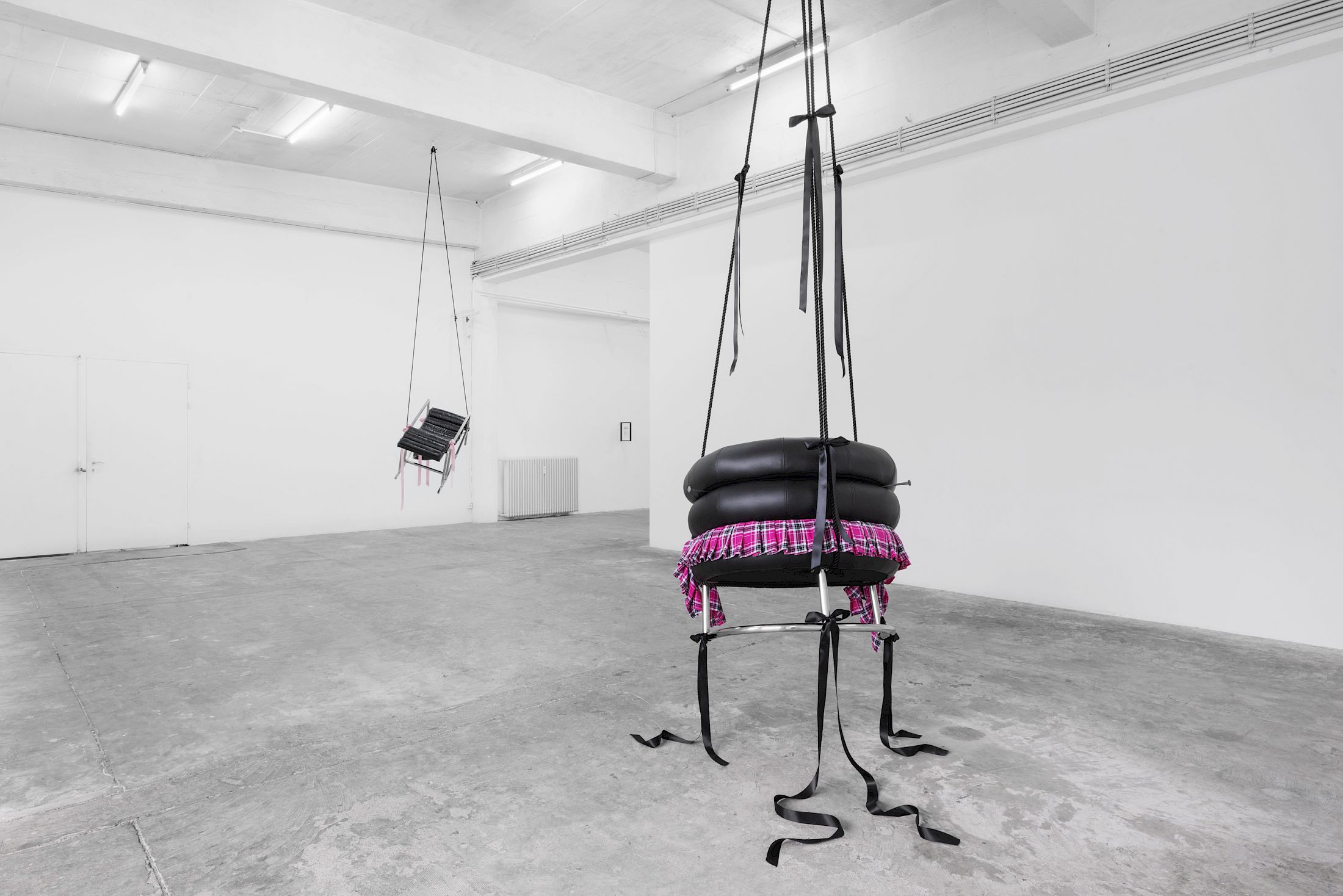 Exhibition View Solo Show Lauryn Youden «I wanna hold the hand inside you ; view on Would you die tonight for love?, 2025, Bibendum Chair (1926), pink plaid skirt, black ribbons, black mooring line, heart locket necklace with red hair, 3x handforged nails, 370 × 93 × 77 cm (suspended)» at CIRCUIT, Lausanne, 2025 / Photo: Aude Mayer / Courtesy: the artist and CIRCUIT