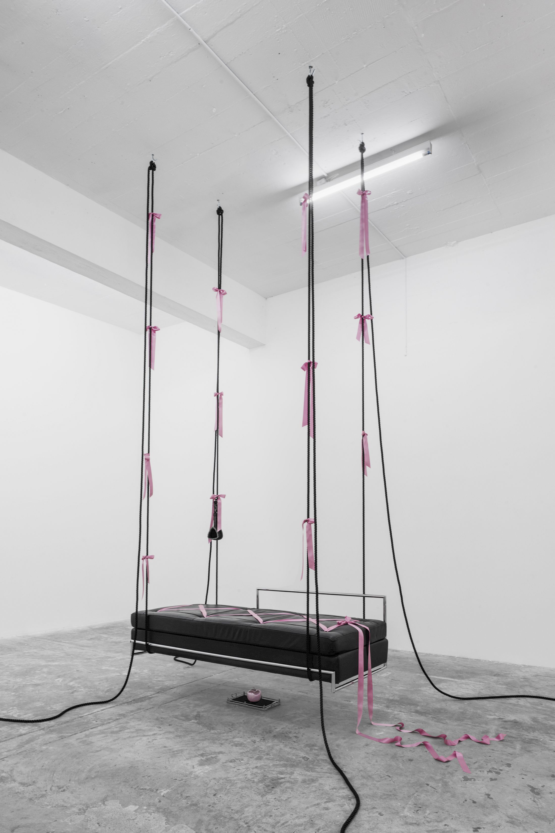 Exhibition View Solo Show Lauryn Youden «I wanna hold the hand inside you ; view on siège d'amour (Edward VII), 2025, Day Bed (c. 1925), pink porcelain apple, velvet tray, rose ribbons, black mooring line, book: Bob Flanagan’s The Pain Journal, vintage lesbian BDSM photograph, horse hair brush, butterfly riding crop, 450 × 192 × 85 cm (suspended)» at CIRCUIT, Lausanne, 2025 / Photo: Aude Mayer / Courtesy: the artist and CIRCUIT