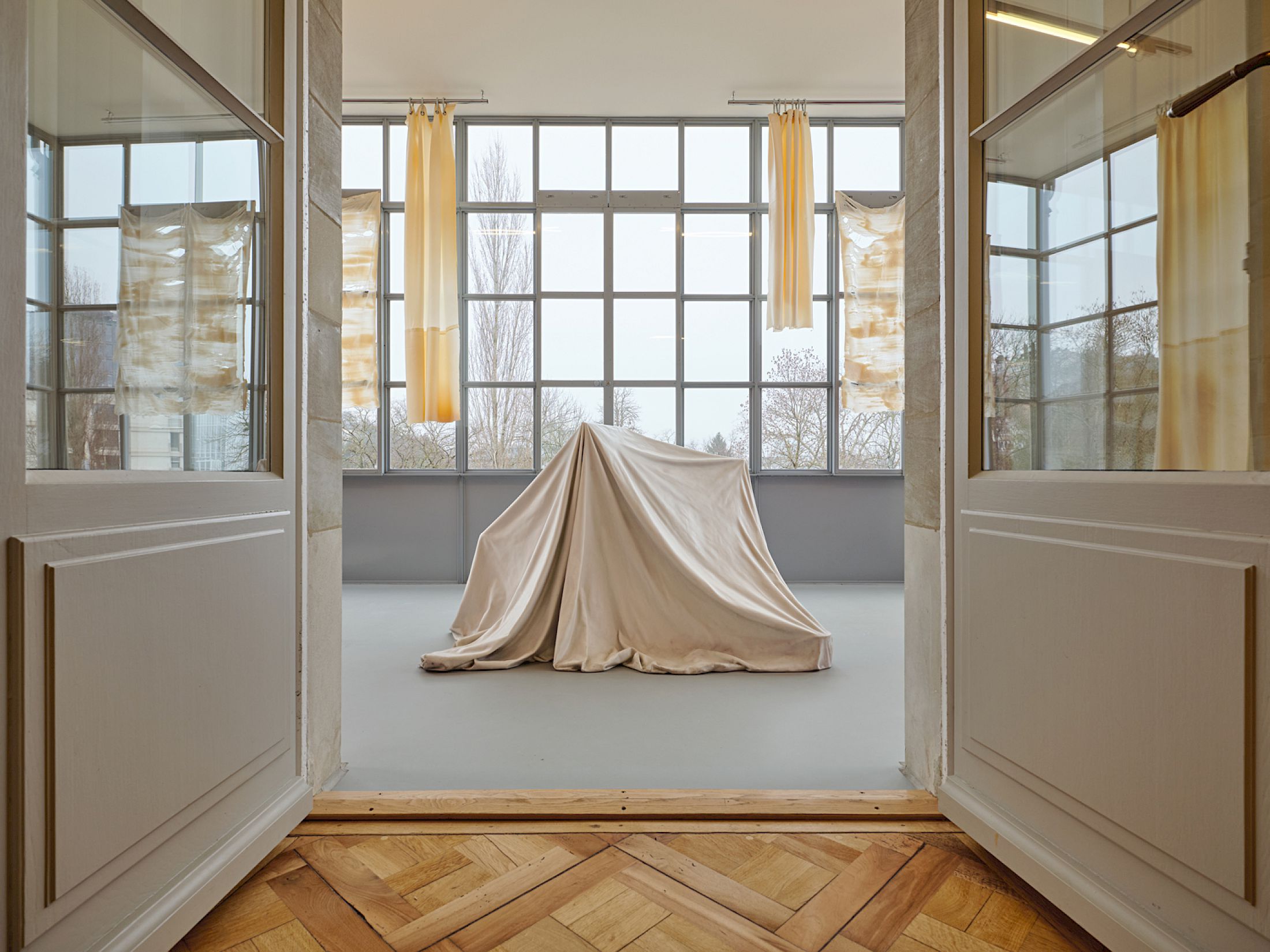 Exhibition View Group Show «Stitches: A Haunted House and Other Ghost Stories ; view on Ryan Gander, I is... (i)., 2012, glass fiber, marble powder, Collection Lionel Aeschlimann ; Li Tavor, Bright Curtains I, II, III, 2025, pigmented latex curtains, aluminum, carabiners» at Villa Bernasconi, Lancy, Geneva, 2026 / Photo: Nicolas Delaroche / Courtesy: the artists and Villa Bernasconi