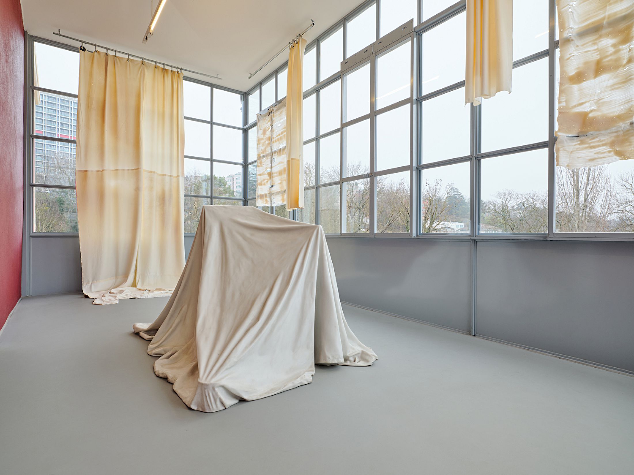Exhibition View Group Show «Stitches: A Haunted House and Other Ghost Stories ; view on Ryan Gander, I is... (i)., 2012, glass fiber, marble powder, Collection Lionel Aeschlimann ; Li Tavor, Bright Curtains I, II, III, 2025, pigmented latex curtains, aluminum, carabiners» at Villa Bernasconi, Lancy, Geneva, 2026 / Photo: Nicolas Delaroche / Courtesy: the artists and Villa Bernasconi