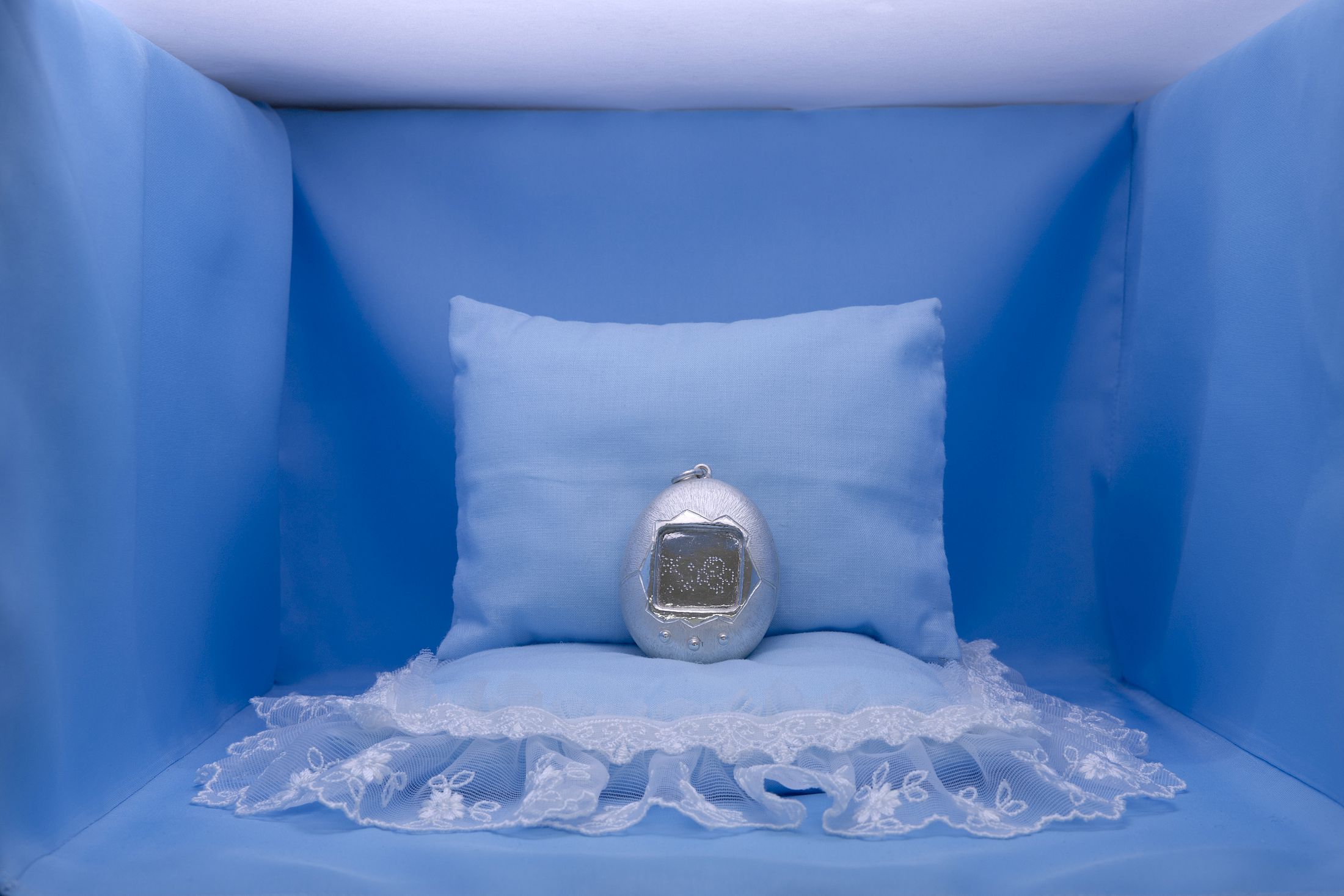 Exhibition View Group Show «Wear a mask and your face grows to fit it ; view on Jennifer Merlyn Scherler, Grave Friend (early generation, international version), 2025, hand-hammered silver, polyester textile, lace, stuffing, Japanese paper, 18 × 28 × 31 cm» at For, Basel, 2025 / Photo: Gina Folly / Courtesy: the artists and For