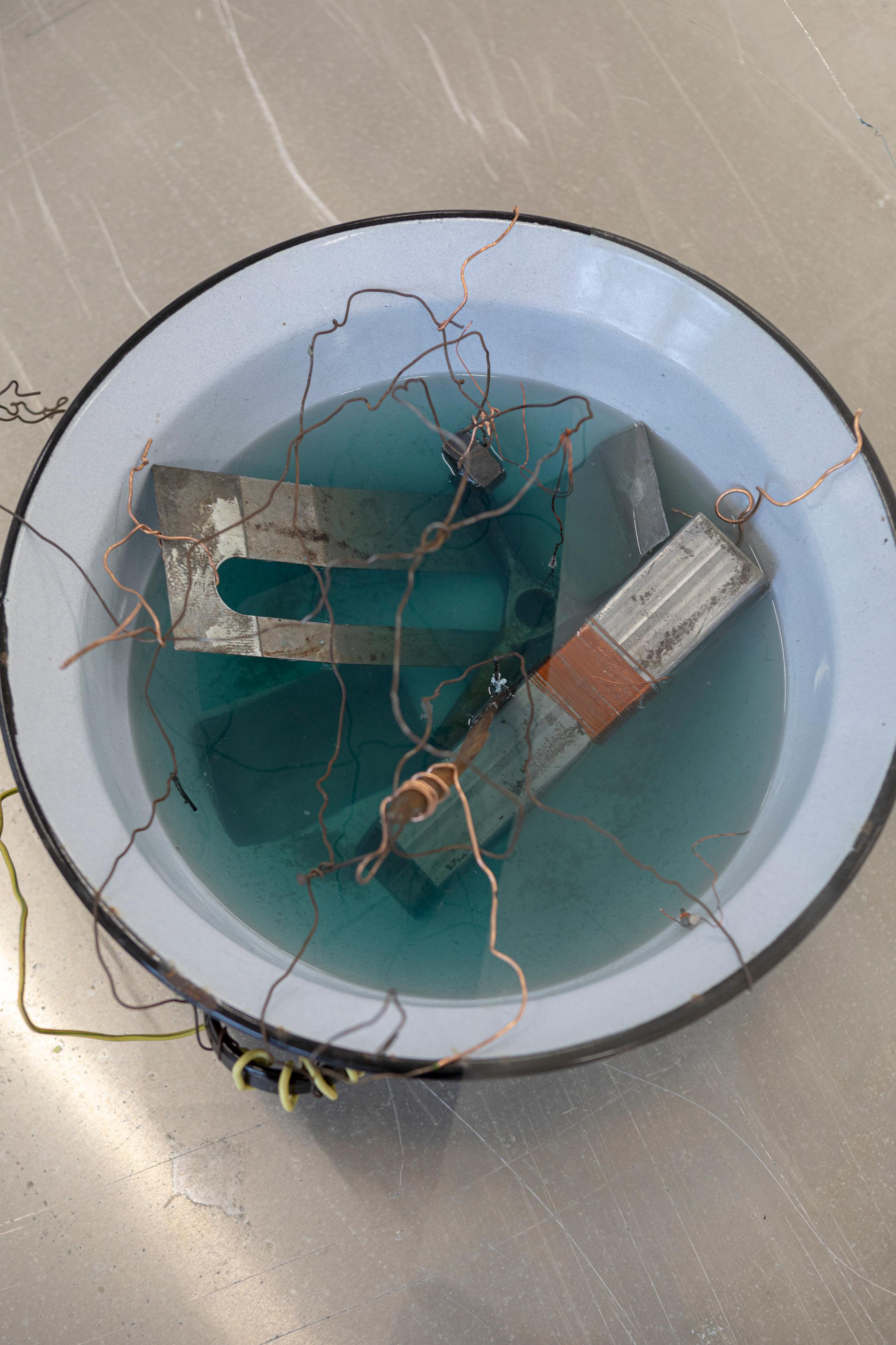 Exhibition View Solo Show Julia Znoj «BASS MY TRESPASS ; view on Setup (Direct Current)(detail), 2025, laboratory power supply, zinc electrolyte, water, paint, steel, aluminum, paper, glue, glass, wire, found objects, size variable» at Krone Couronne, Biel/Bienne, 2025 / Photo: Michal Schorro / Courtesy: the artist and Krone Couronne