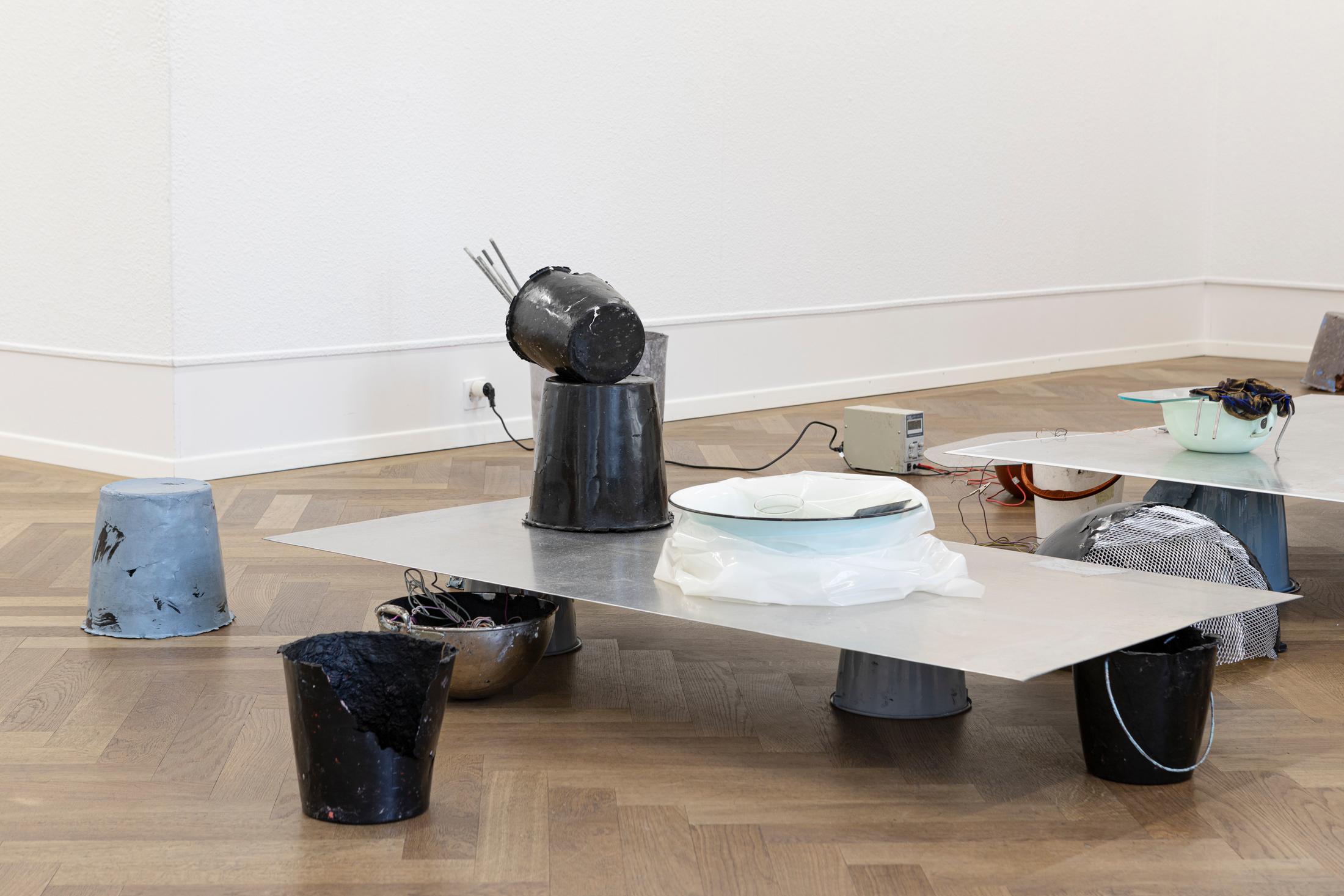 Exhibition View Solo Show Julia Znoj «BASS MY TRESPASS ; view on Setup (Direct Current), 2025, laboratory power supply, zinc electrolyte, water, paint, steel, aluminum, paper, glue, glass, wire, found objects, size variable» at Krone Couronne, Biel/Bienne, 2025 / Photo: Michal Schorro / Courtesy: the artist and Krone Couronne