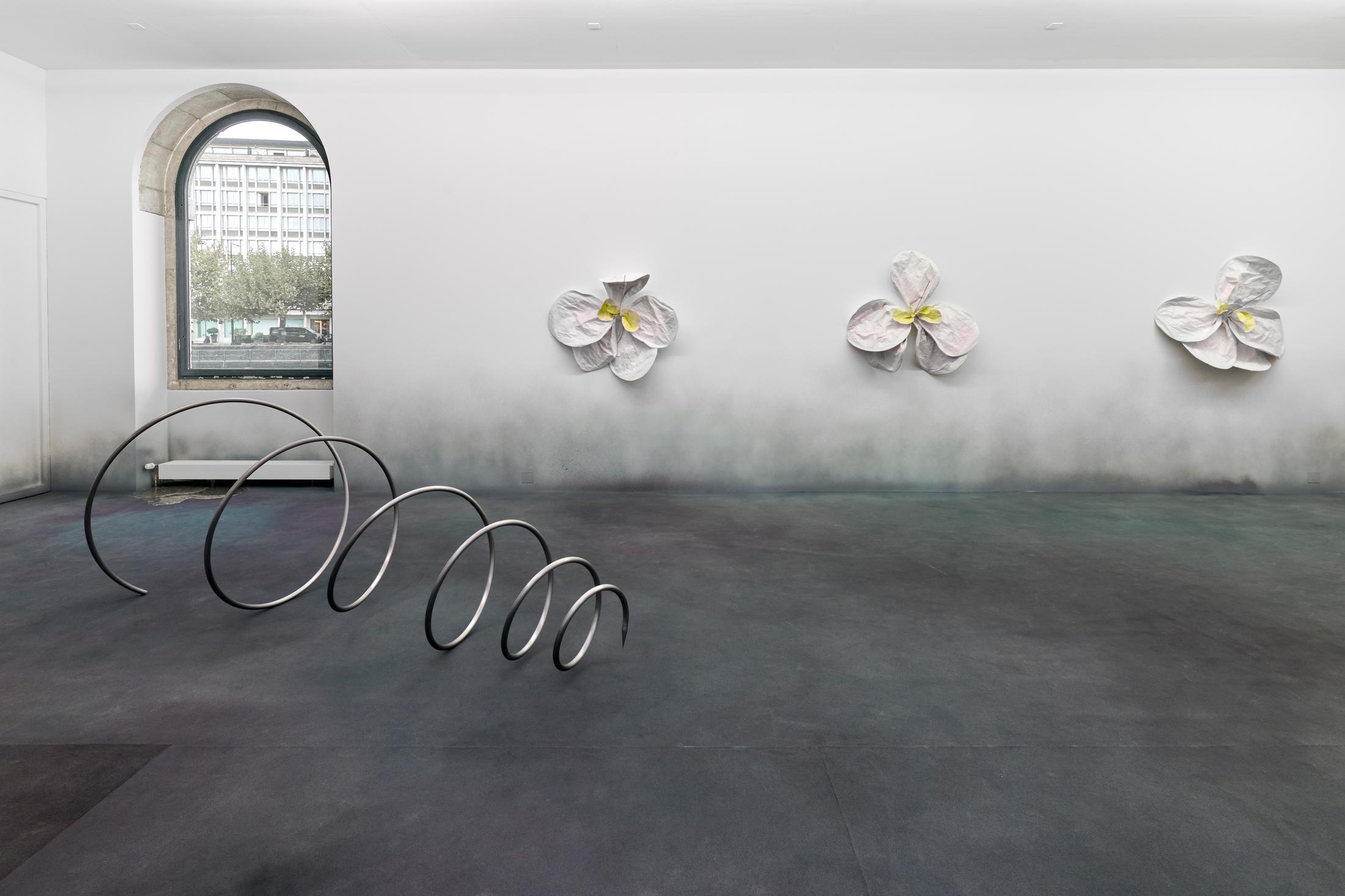 Exhibition View Duo Show Marlène Charpentié and Sophie Conus «DOWN THE RABBIT HOLE; view on (Spirale) Out of Wonders, 2024, Steel, 295cm x 110cm x 105cm, and (Fleurs) Killer Queens, 2024, Steel, papier mâché, iron wire, tape, paint, varnish, 4 pieces of 125cm x 125cm x 55cm» at Halle Nord, Geneva, 2024 / Photo: Thomas Maisonnasse / Courtesy: the artists and Halle Nord