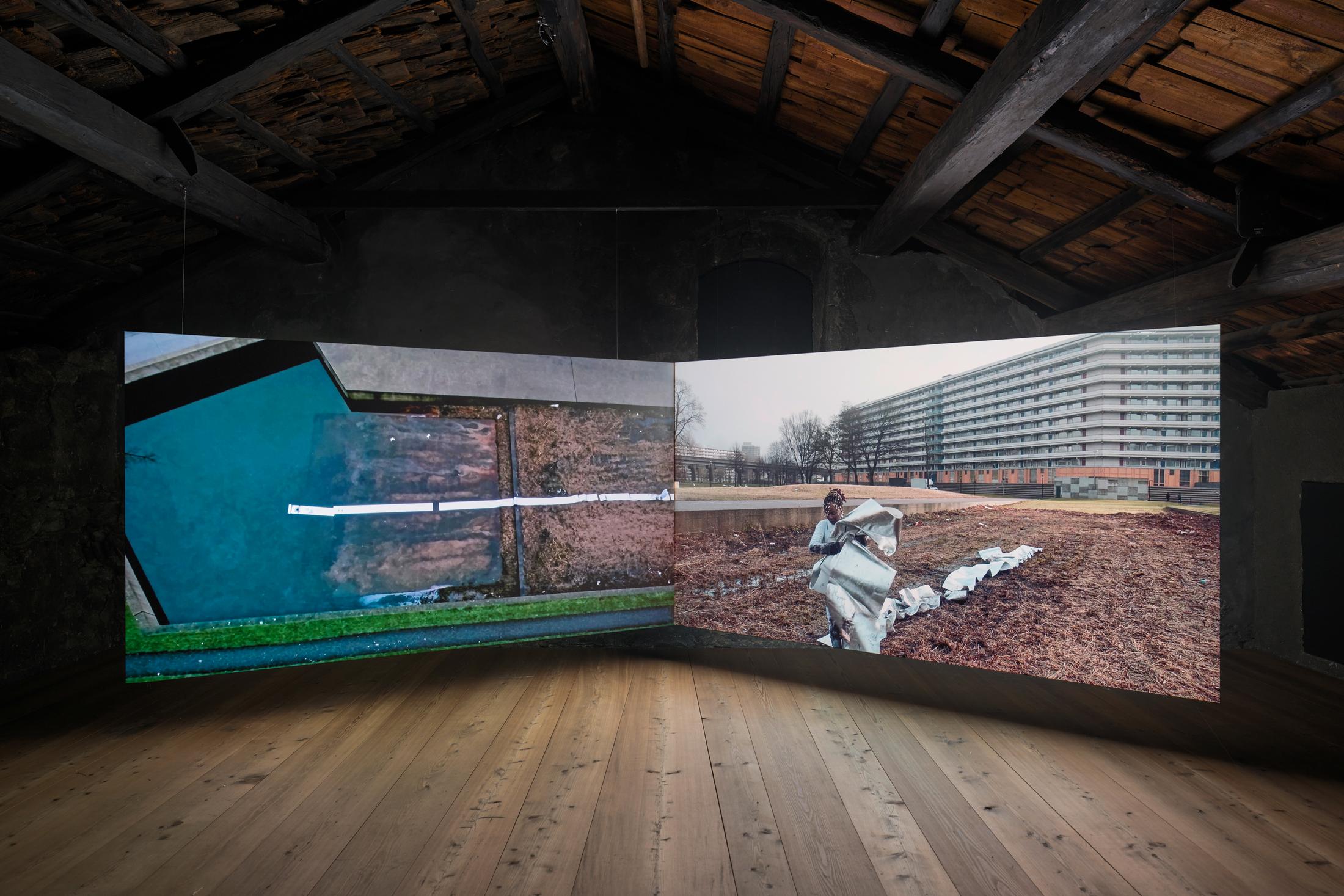 Exhibition View donna Kukama Solo Show «transcendence; view on donna Kukama, Chapter Q: Dem Short-Short falls, 2017 - 2018, Video double projection, Film Still, Part 1: 12 min 10 sec., Part 2: 12 min 11 sec» at Galerie Tschudi, Zuoz, 2023 / Photo: Ralph Feiner / Courtesy: the artist and Galerie Tschudi