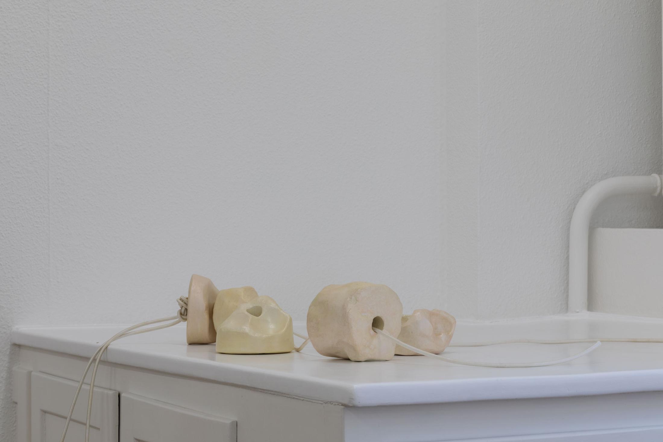 Exhibition View Leolie Greet with Amélie Bodenmann, Anina Müller and Nina Rieben Show «mumbles slide along the sleeve; view on Leolie Greet, THE TONGUE (licking words to pearls), 2023, plaster, gouache, varnish, pearlescent pigments, elastic thread, steel» at Krone Couronne, Biel, 2023 / Photo: Guadalupe Ruiz / Courtesy: the artist and Krone Couronne