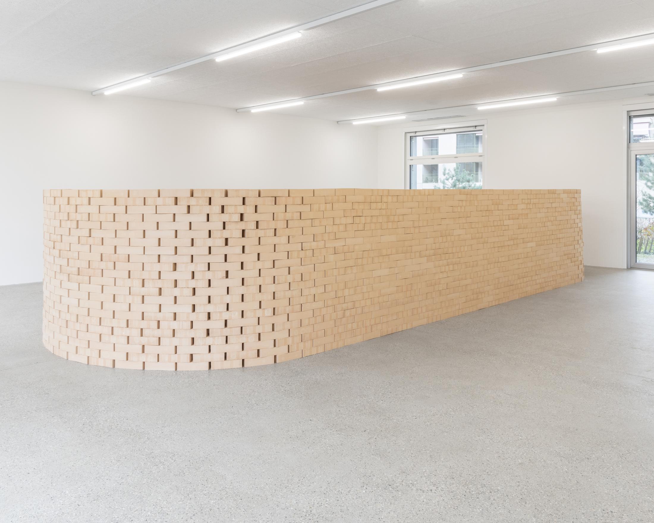 Exhibiton View Solo Show Shirin Yousefi «BAZM; view on BAZM (wall), 2024, 2400 bricks cellar floor, 5.1 home cinema, DVD player, dimensions variable» at CALM – Centre d’Art La Meute, Lausanne, 2024 / Photo: Théo Dufloo / Courtesy: the artist and CALM – Centre d’Art La Meute