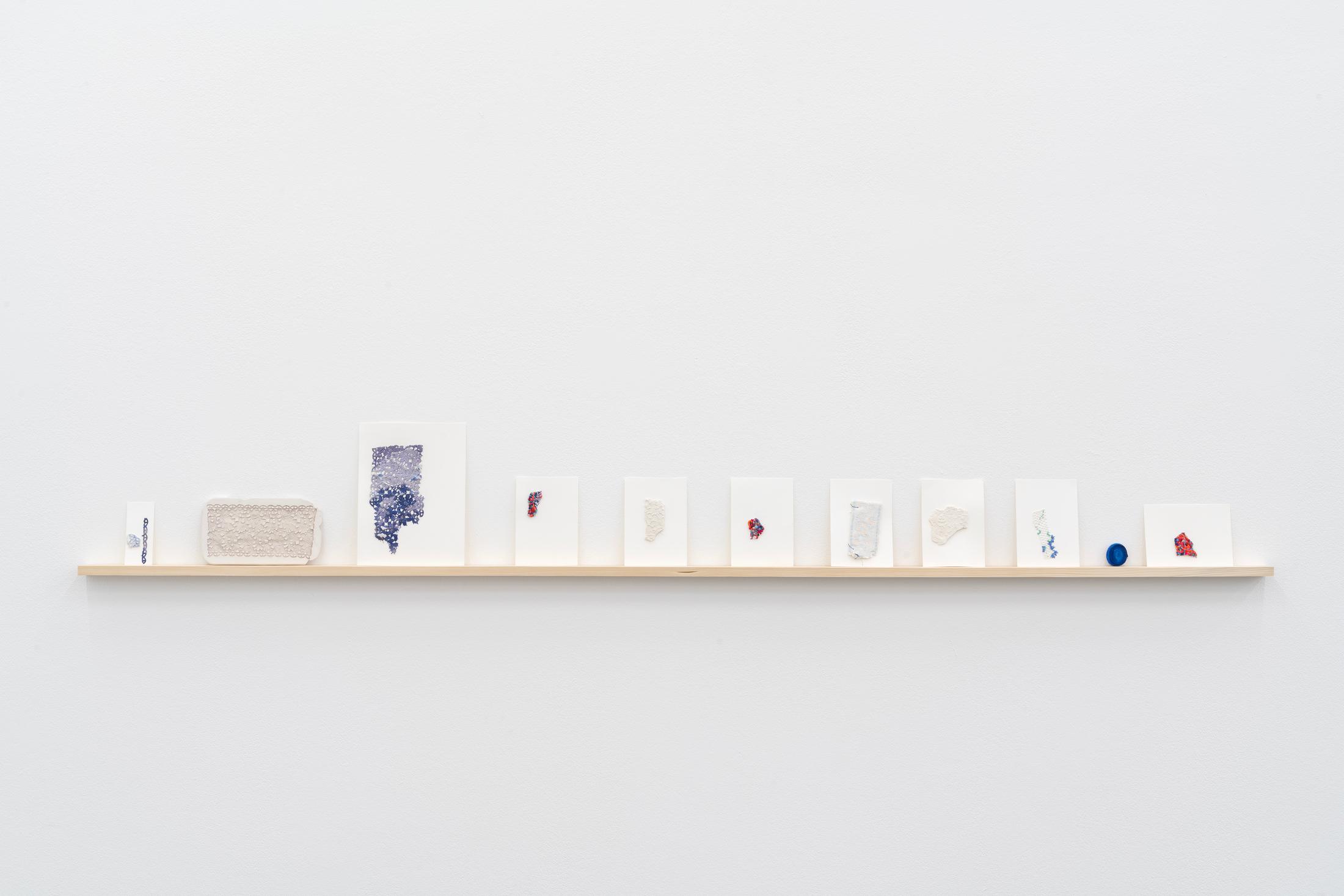 Exhibition View Double Show Majd Abdel Hamid «Resonances ; view on It's still too soon to leave, 2023, Cotton and silk thread on readymades, linen, cotton, postcards, plaster, indigo dye, various sizes and Ode to the sea folded waves, 2025, Silk, acrylic ink, 3 x 4 cm» at Kunst Halle Sankt Gallen, St. Gallen, 2025 / Photo: E. Sommer / Courtesy: the artist and 16 Avril, Paris