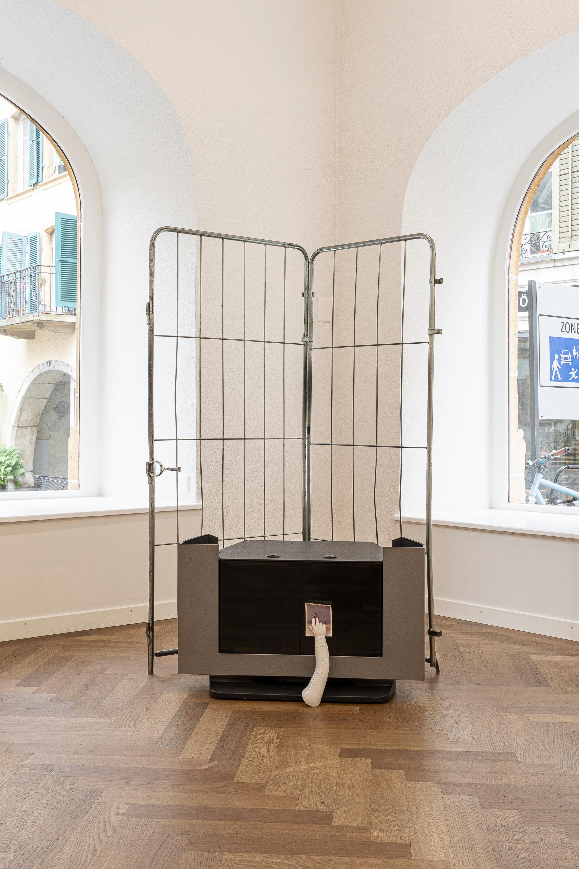 Exhibition View Group Show «THE GLEANERS; view on Sophie Jung
Gut strings a corner a coroner [...], 2023, Personal photograph, baby mannequin hand, cathode-ray tube tv cabinet, trolly gates, tennis racket» at Krone Couronne, Biel, 2023 / Photo: Michal Florence Schorro / Courtesy: the artist and Krone Couronne