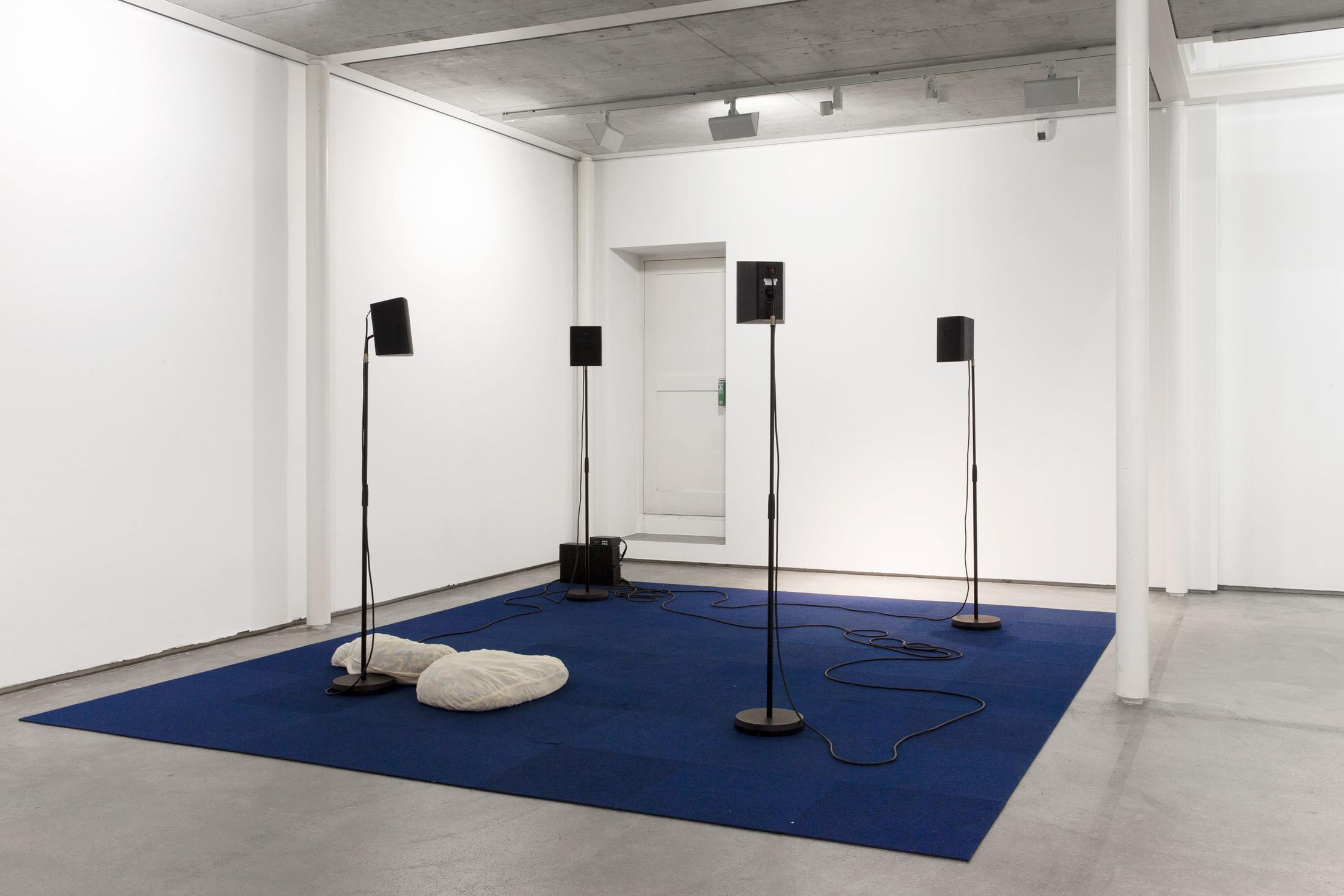 Exhibition View Group Show «Contrology; view on Martina Mächler, 71 % (play), 2018, Four loudspeakers with audio loop, tripods, carpet, cushions, Dimensions variable» at Kunst Raum Riehen, 2021 / Photo: Gina Folly / Courtesy: the artists and Kunstraum Riehen