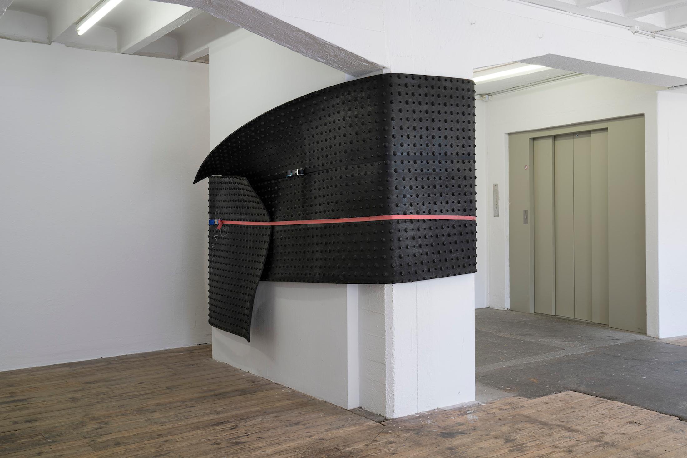 Exhibition View Group Show «Issue de secours; view on Val Minnig, Rubber coat, 2017, Kälber Neugummi Rollmatte schwarz mit Noppen, SpanSet» at Binz39, Zürich, 2021 / Photo: Claude Barrault / Courtesy: the artists and Binz39