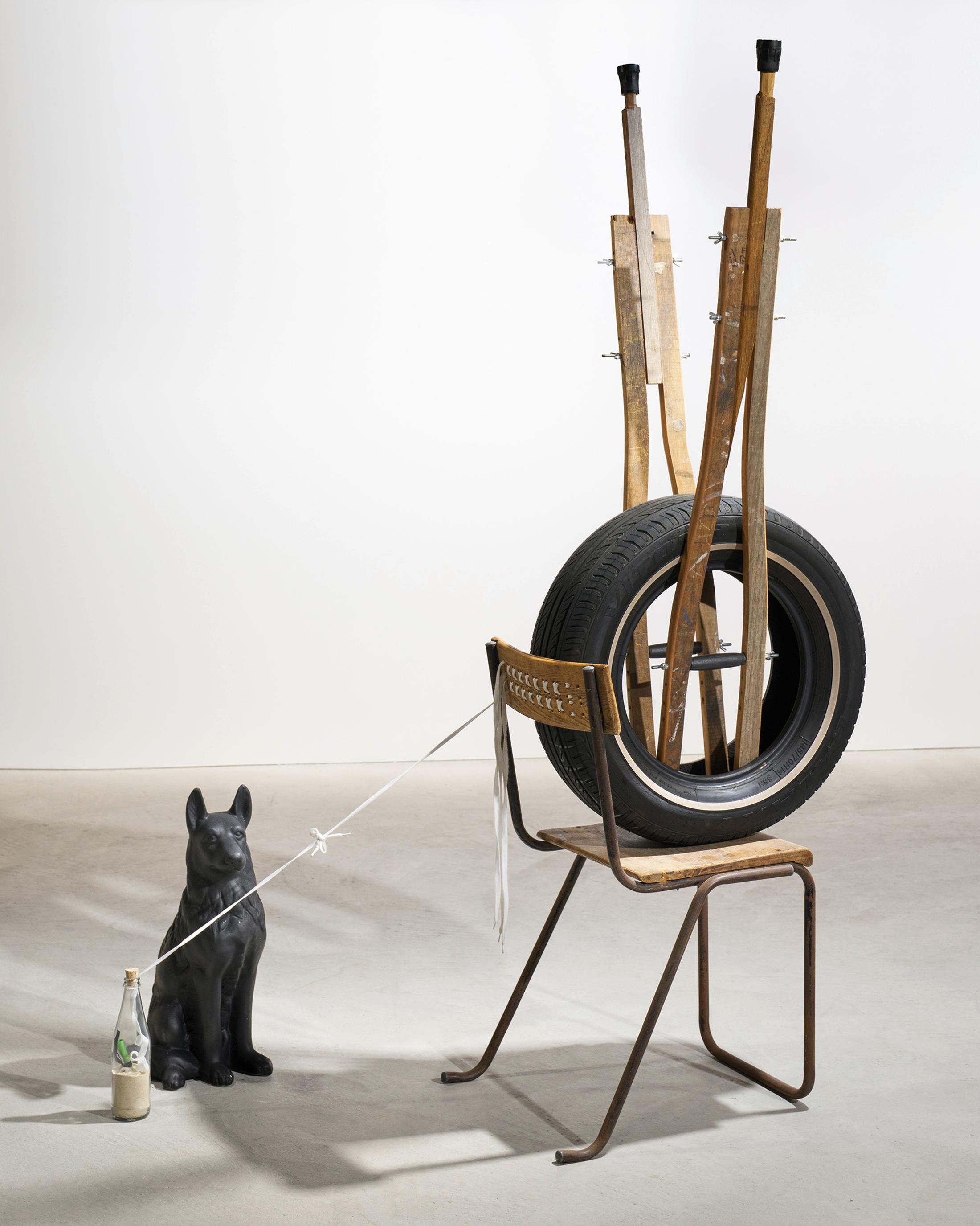 Exhibition View Kemang Wa Lehulere Solo Show «Where Did the Sky Go?; view on Kemang Wa Lehulere, The Conjunction 2, 2020, crutches from salvaged shool desk, car tyre, salvaged school chair, porcelain dog, bottle with sand, shoe laces, 179 x 128 x 70 cm and dog» at Galerie Tschudi, Zuoz, Engadin, 2020 / Photo: Ralph Feiner / Courtesy: the artist and Galerie Tschudi
